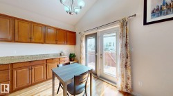 Kitchenette featuring wood-finish flooring, abundant wood cabinetry, granite-patterned countertops, and double glass-paneled patio doors - 