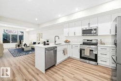 Bright kitchen featuring white cabinetry, stainless steel appliances, a white tile backsplash, and light wood-finish flooring - 