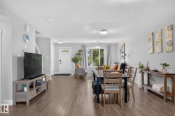 Open-concept living space featuring wood-finish flooring, recessed lighting, and a white paneled entry door - 