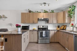 Modern kitchen featuring wood-finish cabinetry, speckled countertops, and stainless steel appliances - 