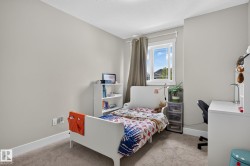 Neutral-toned room featuring a window with white trim, light gray walls, white baseboards, and soft carpet flooring - 