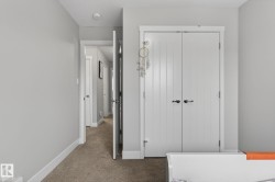 Interior hallway with light gray walls, white trim, paneled interior doors, and carpet flooring - 