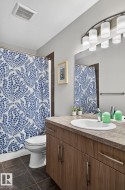 Bathroom featuring a single vanity with wood-finish cabinetry, a white oval sink, and a laminate countertop - 