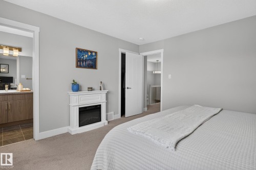 Carpeted bedroom with light gray walls, an electric fireplace, and white trim - 33 Durrand Bend, Fort Saskatchewan, AB 