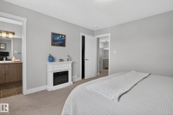 Carpeted bedroom with light gray walls, an electric fireplace, and white trim - 