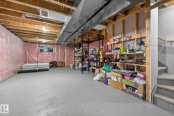 Unfinished basement featuring exposed wood joists and structural beams, along with a painted concrete floor - 