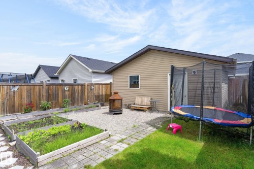 Backyard featuring a graveled patio area, raised garden beds, and a wood privacy fence - 33 Durrand Bend, Fort Saskatchewan, AB 