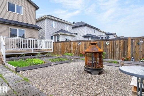 Backyard featuring a wooden deck with white railing, raised garden beds, and a gravel patio area - 33 Durrand Bend, Fort Saskatchewan, AB 