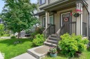 Inviting front entrance featuring a covered porch, wood-look siding, and a wooden staircase with railings - 33 Durrand Bend, Fort Saskatchewan, AB 