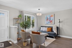 Bright living space featuring wood-finish flooring, light grey wall paint, and white trim - 