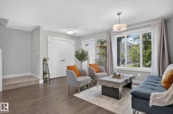 Living area featuring wood-finish flooring, light gray wall paint, and a large multi-pane window - 