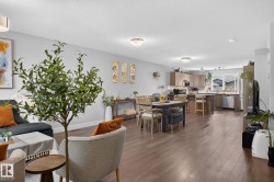 Open-concept living space featuring wood-finish flooring, a dining area, and a kitchen with light-toned cabinetry and stainless steel appliances - 