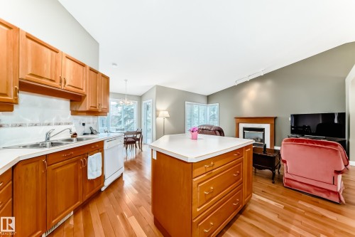 Open-concept living space featuring wood-finish flooring, a kitchen island with storage, light wood cabinetry, a built-in fireplace, and vaulted ceilings - 29 929 Picard Drive, Edmonton, AB - Indoor Photo Showing Kitchen With Double Sink