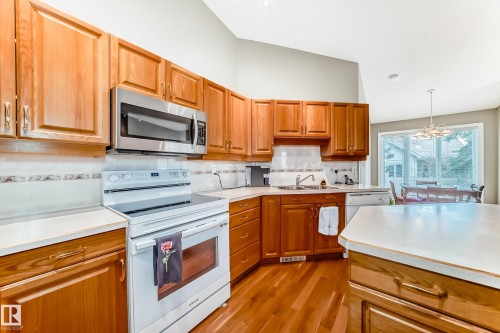 Kitchen featuring warm wood cabinetry, light countertops, and wood-finish flooring - 29 929 Picard Drive, Edmonton, AB - Indoor Photo Showing Kitchen With Double Sink