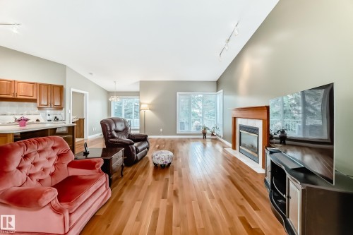 Open concept living space featuring wood-finish flooring, a fireplace with a wood mantle and tile surround, and multiple windows - 29 929 Picard Drive, Edmonton, AB - Indoor Photo Showing Living Room With Fireplace