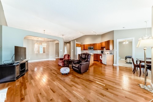Open-concept living area featuring wood-finish flooring, vaulted ceilings, and an arched doorway leading to a separate room - 29 929 Picard Drive, Edmonton, AB - Indoor