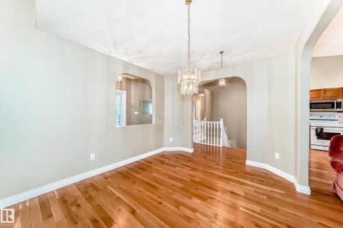 Expansive room featuring wood-finish flooring, light neutral wall paint, and white baseboards - 29 929 Picard Drive, Edmonton, AB - Indoor