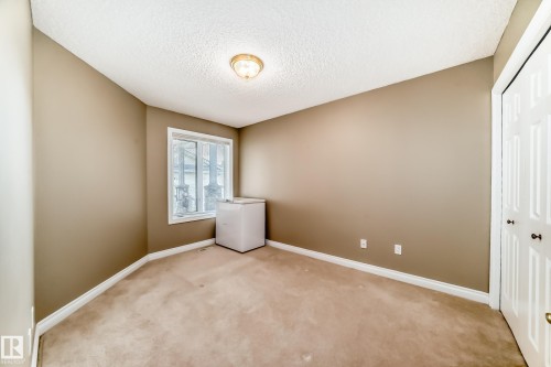 Carpeted interior room featuring neutral wall tones, a ceiling-mounted light fixture, white trim, a single window, and a bifold closet door - 29 929 Picard Drive, Edmonton, AB - Indoor Photo Showing Other Room