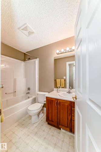 Bathroom featuring a white tub/shower combination, toilet, and a vanity with wood-finish cabinetry and a white countertop - 29 929 Picard Drive, Edmonton, AB - Indoor Photo Showing Bathroom