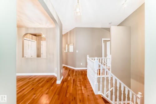 Hardwood flooring extending throughout, complemented by a white baluster staircase and arched wall openings - 29 929 Picard Drive, Edmonton, AB - Indoor Photo Showing Other Room