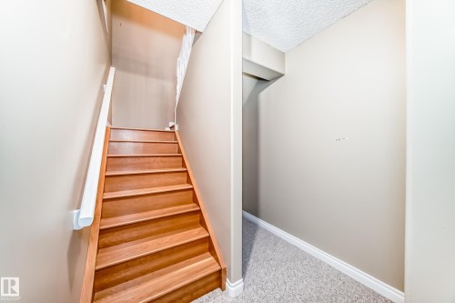 Wood-finish staircase with white risers and handrail, neutral painted walls, and textured ceiling finish - 29 929 Picard Drive, Edmonton, AB - Indoor Photo Showing Other Room
