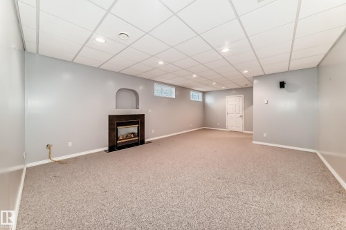 Spacious finished lower level featuring a fireplace with a dark surround, neutral wall-to-wall carpeting, recessed lighting, and a dropped ceiling - 29 929 Picard Drive, Edmonton, AB - Indoor