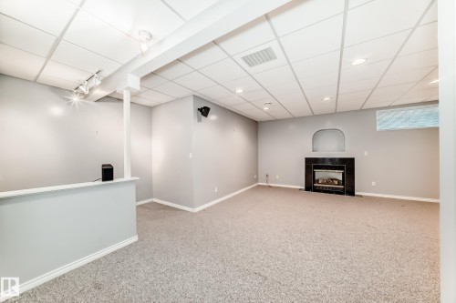 Spacious finished room featuring a dark fireplace surround, an arched wall niche, recessed lighting, track lighting, and soft carpet flooring - 29 929 Picard Drive, Edmonton, AB - Indoor