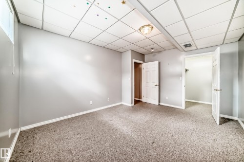 Spacious interior room featuring light grey walls, textured carpet flooring, white trim, and a drop-tile ceiling with recessed lighting - 29 929 Picard Drive, Edmonton, AB - Indoor Photo Showing Other Room