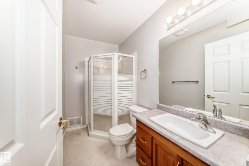 Bathroom featuring a wood vanity with integrated sink, a corner glass shower enclosure, and neutral wall paint - 29 929 Picard Drive, Edmonton, AB - Indoor Photo Showing Bathroom