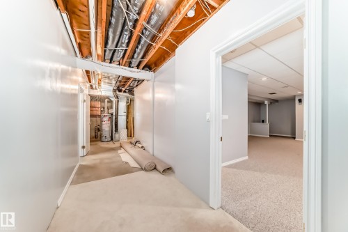 Unfinished basement area with exposed ceiling joists and utility access, including a water heater and HVAC components - 29 929 Picard Drive, Edmonton, AB - Indoor