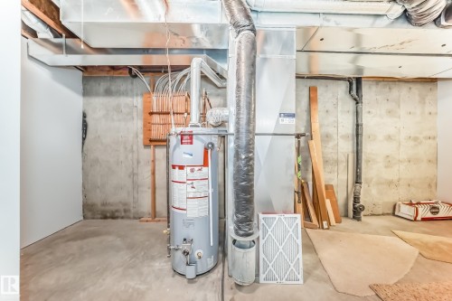 Utility area featuring a water heater, furnace, exposed ductwork, concrete floor, and unfinished concrete walls - 29 929 Picard Drive, Edmonton, AB - Indoor Photo Showing Basement