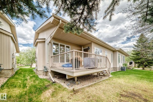 Rear exterior featuring a spacious wood deck with railing and stairs, tan siding, multiple large windows, and a manicured lawn - 29 929 Picard Drive, Edmonton, AB - Outdoor With Deck Patio Veranda