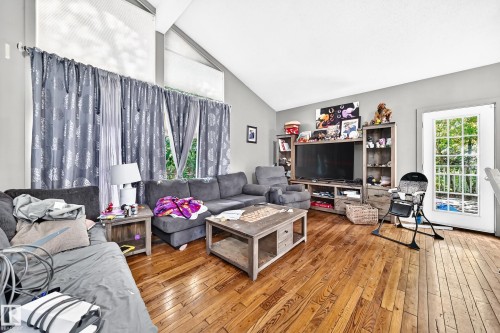 Living area featuring wood-finish flooring, vaulted ceilings, and ample natural light from large windows - 199 Westridge Road, Edmonton, AB 