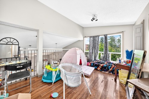 Spacious room featuring wood-finish flooring, a vaulted ceiling, and multiple windows with exterior views - 199 Westridge Road, Edmonton, AB 