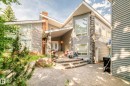 Multi-level exterior featuring siding and stone accents, a prominent brick chimney, large windows, and a covered entry with double doors - 199 Westridge Road, Edmonton, AB 