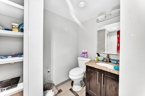 Bathroom featuring a white toilet, dark wood-finish vanity with a granite-style countertop, and a built-in medicine cabinet with integrated lighting - 199 Westridge Road, Edmonton, AB 