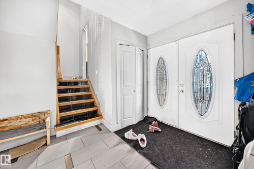 Entryway featuring double doors with decorative glass inserts, light wood-finish stairs, and light-toned tile flooring - 199 Westridge Road, Edmonton, AB 
