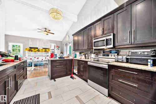 Kitchen featuring dark wood cabinetry, light-toned countertops, and stainless steel appliances - 199 Westridge Road, Edmonton, AB 