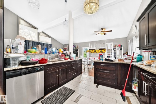 Kitchen featuring dark wood cabinetry, light-toned granite countertops, and stainless steel appliances - 199 Westridge Road, Edmonton, AB 