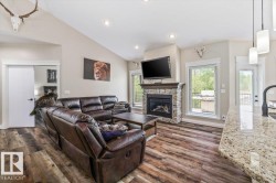 Open-concept living area featuring vaulted ceilings and wood-finish flooring - 