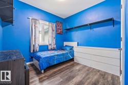 Bedroom featuring wood-finish flooring, a double-paned window, and a built-in wall shelf - 