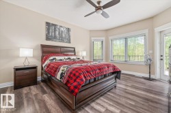 Spacious bedroom featuring wood-finish flooring, a ceiling fan, and multiple windows with white trim - 