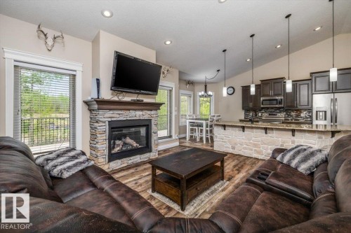 Open-concept living space with wood-finish flooring, a stone-faced fireplace, and recessed lighting - #6 2406 Twp Road 540, Rural Lac Ste. Anne County, AB - Indoor Photo Showing Living Room With Fireplace