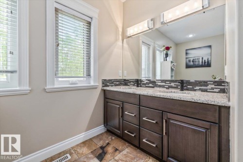 Double vanity with granite-style countertop, dual integrated sinks, and matte black fixtures - #6 2406 Twp Road 540, Rural Lac Ste. Anne County, AB - Indoor Photo Showing Bathroom