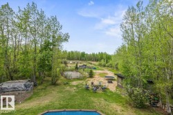 Expansive outdoor living area featuring a large inground pool with blue tile surround, a spacious grassy lawn, and mature trees - 