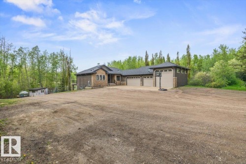 Two-story residential structure featuring a stone and siding exterior, a multi-car garage with three overhead doors, and a dark shingled roof - #6 2406 Twp Road 540, Rural Lac Ste. Anne County, AB - Outdoor