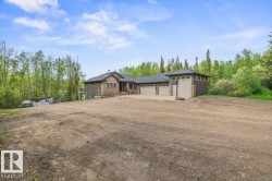 Two-story residential structure featuring a stone and siding exterior, a multi-car garage with three overhead doors, and a dark shingled roof - 