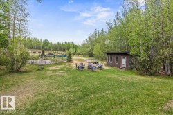 Expansive grassy area with a detached accessory building featuring multiple windows and a single entry door - 