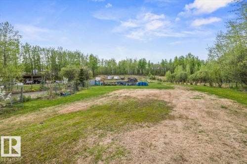 Expansive green space with distant tree lines, featuring a partial gravel driveway and a fenced area - #6 2406 Twp Road 540, Rural Lac Ste. Anne County, AB - Outdoor With View