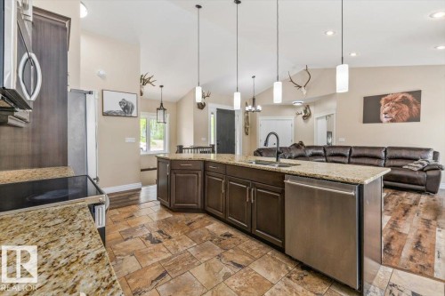 Open-concept kitchen featuring an expansive island with a built-in sink, granite countertops, and dark wood cabinetry - #6 2406 Twp Road 540, Rural Lac Ste. Anne County, AB - Indoor Photo Showing Kitchen With Upgraded Kitchen